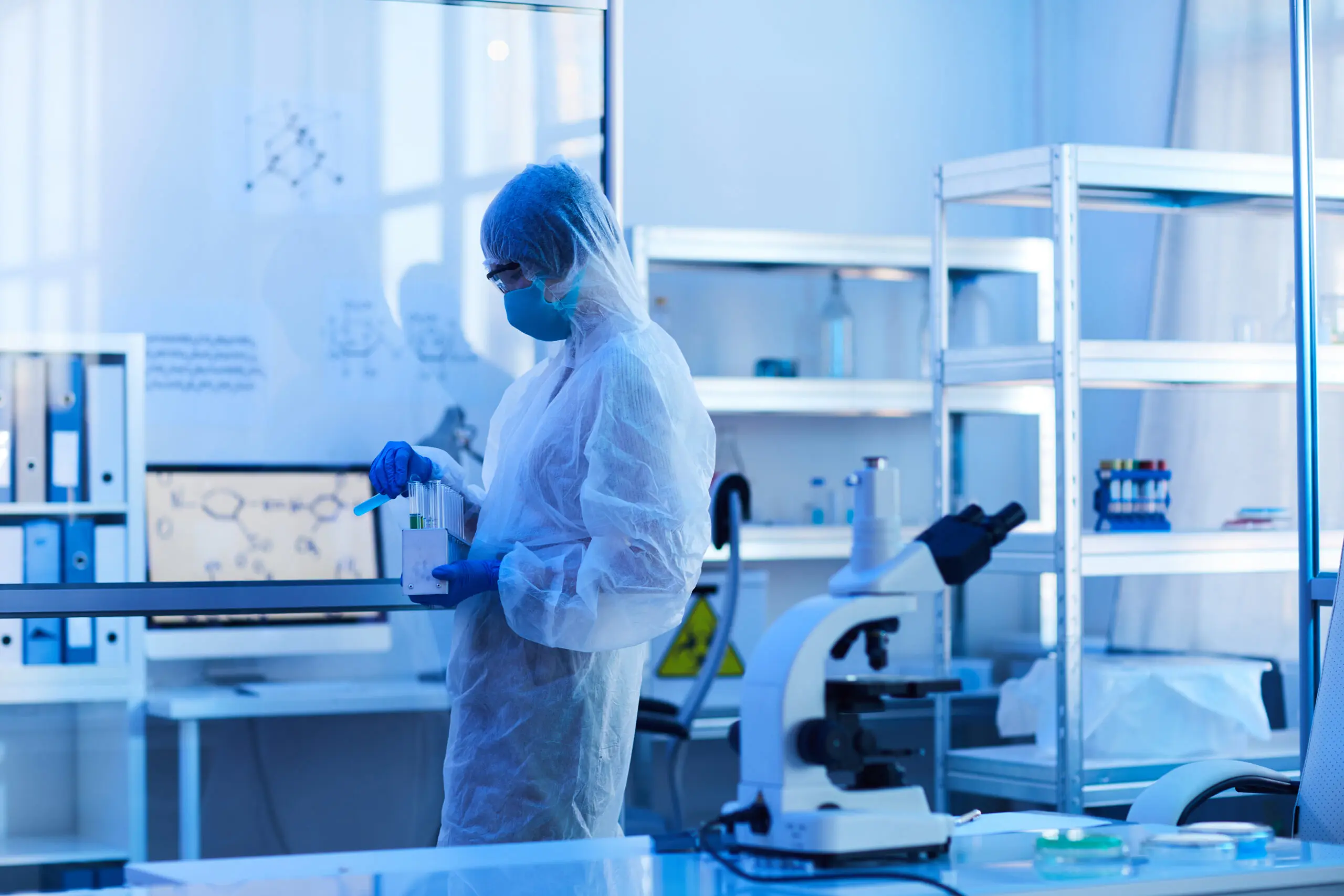Scientist in protective coat holding test tube with samples in